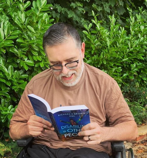 A handsome young man (me) reading Disability is Other People